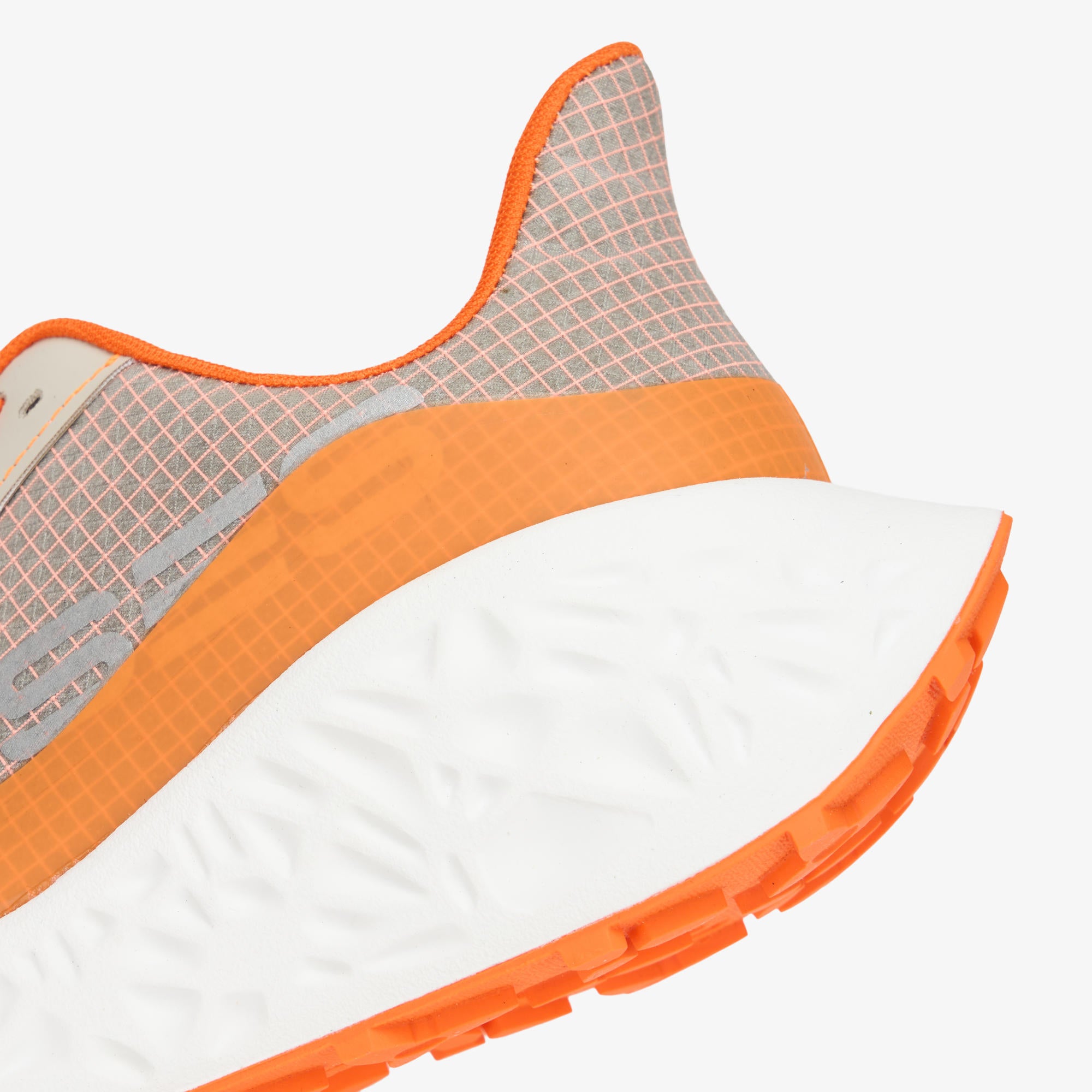 Close-up of a running shoe showing the heel and midfoot area, with a white cushioned sole, bright orange midsole and outsole accents, and a light gray mesh upper.