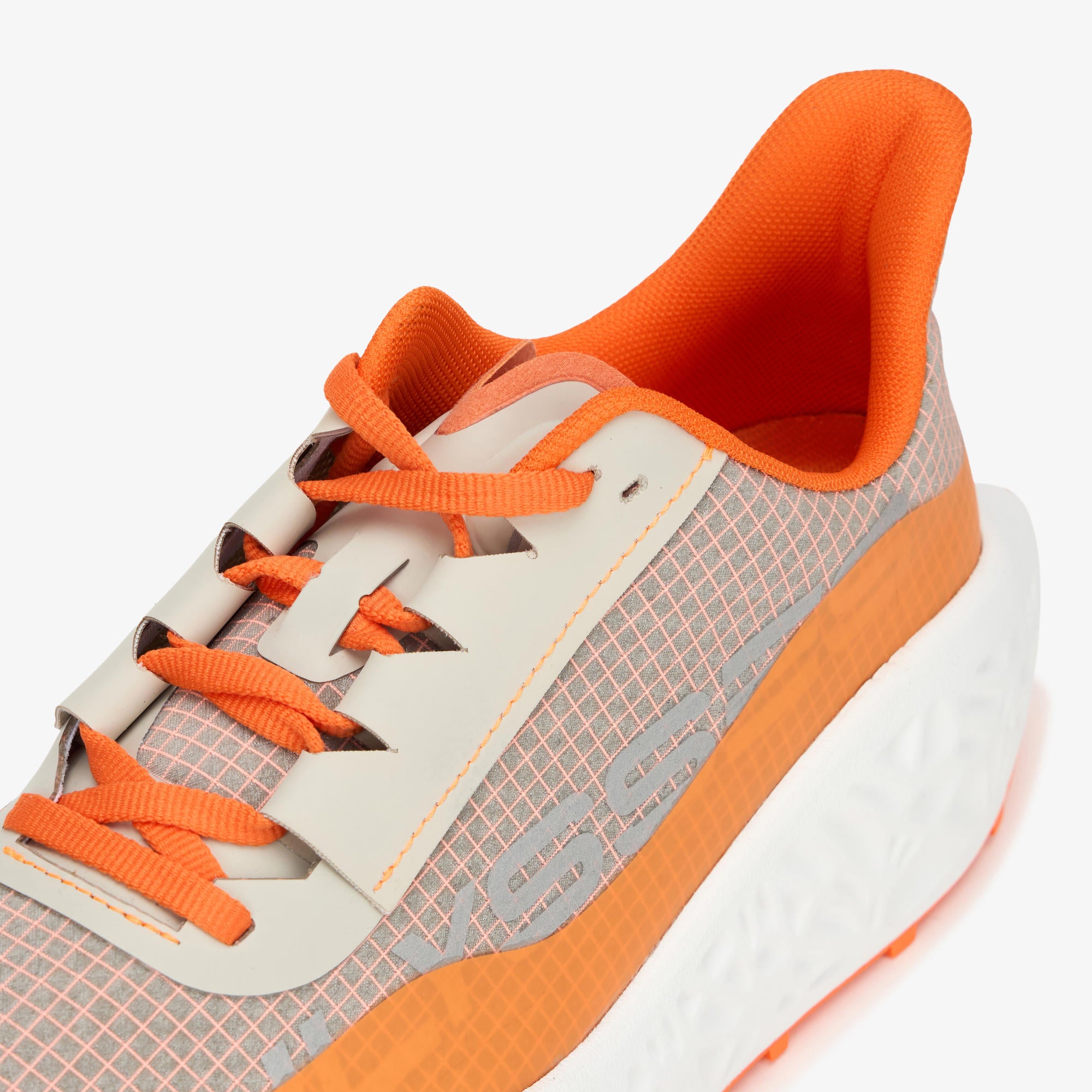 A close-up of a running shoe featuring a gray and white mesh upper, bright orange laces, an orange heel collar, and a chunky white midsole with an orange accent.