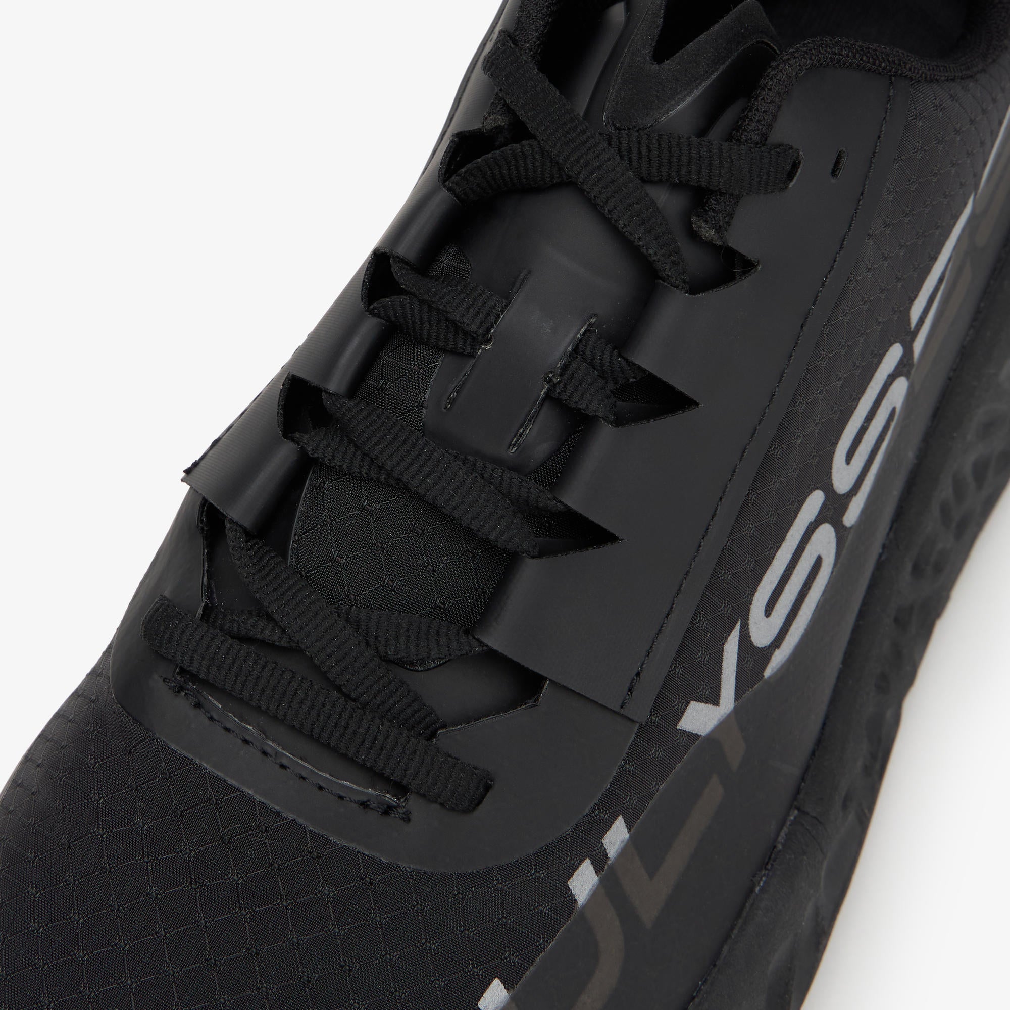 Close-up of a black athletic shoe with black laces and a large white 'ULYSSES' logo on the side, photographed against a clean white background.