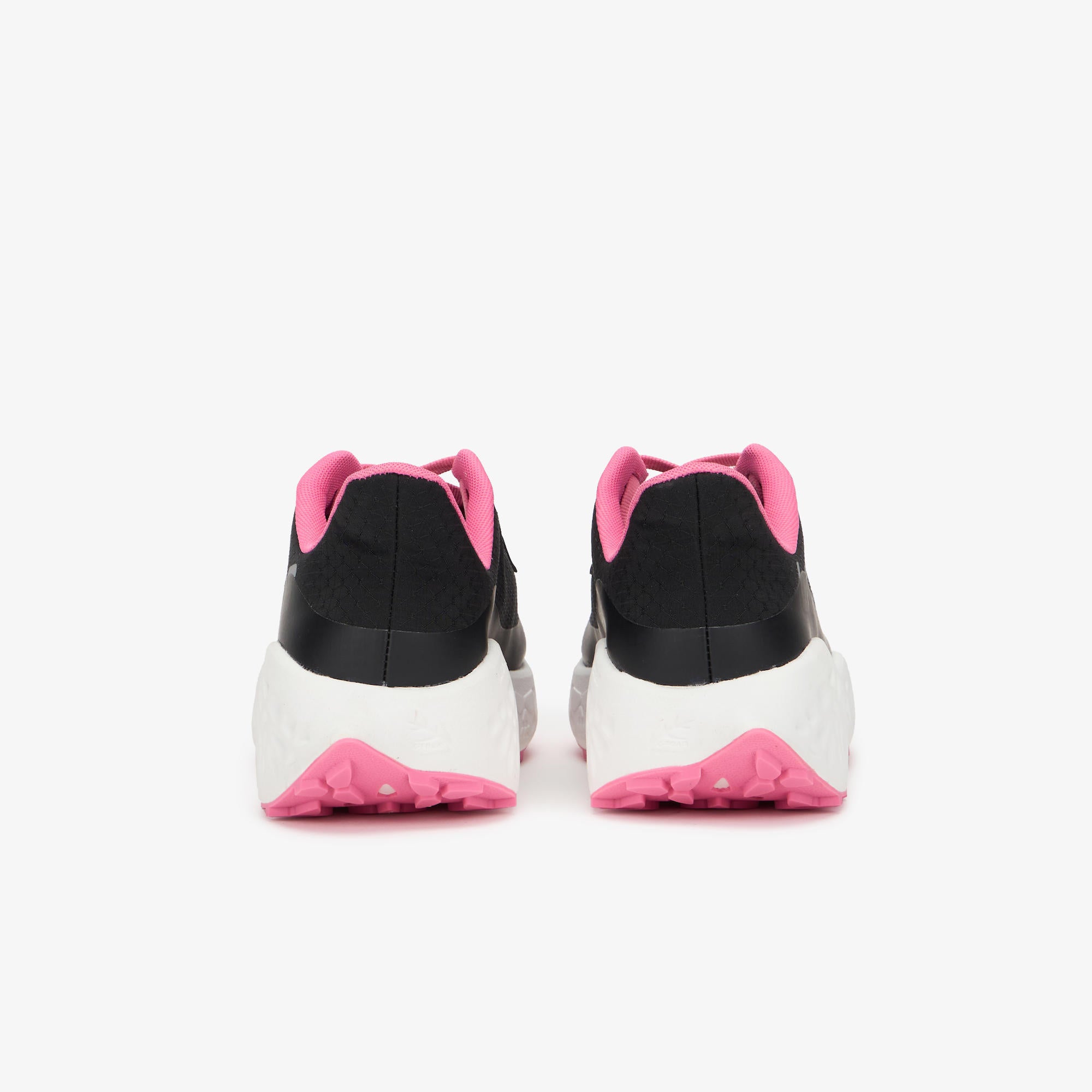 A pair of black and white sneakers viewed from the back, featuring vibrant pink accents on the collar lining, outsole, and heel tab, set against a clean white background.