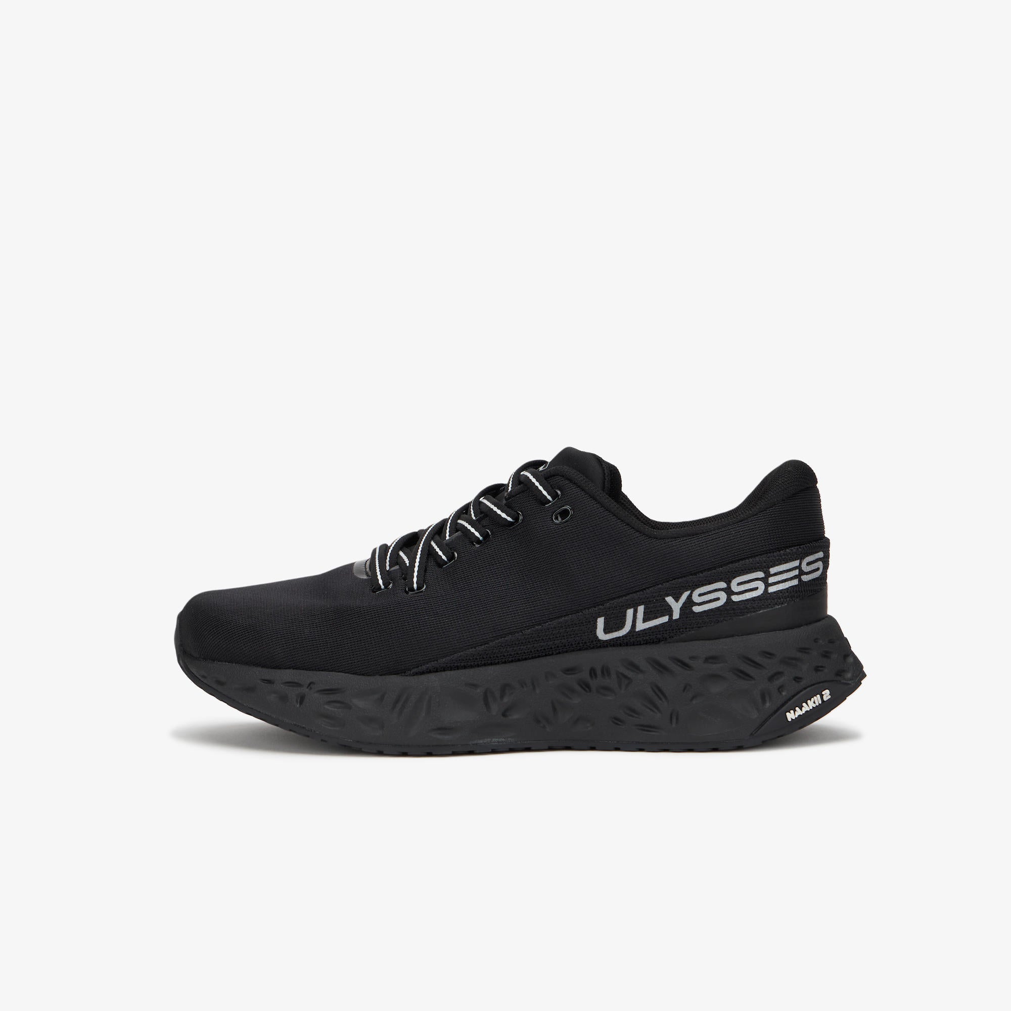 A black ULYSSES NAAKII  running shoe shown from the side profile against a clean, light gray background. The shoe features a black upper, black laces, and a black sole with textured details, including the brand name 'ULYSSES' printed in white on the side.