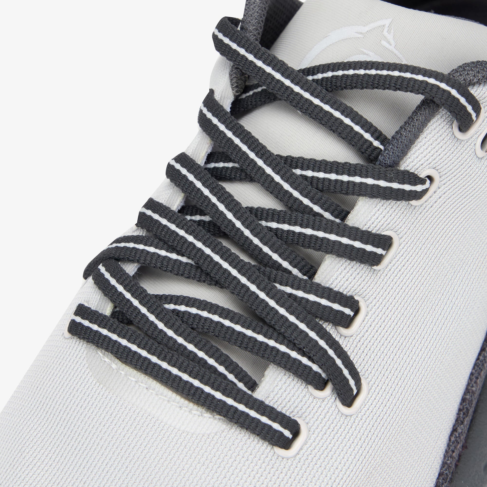 Close-up of a white athletic shoe with dark gray laces featuring white stripes, set against a clean white background.