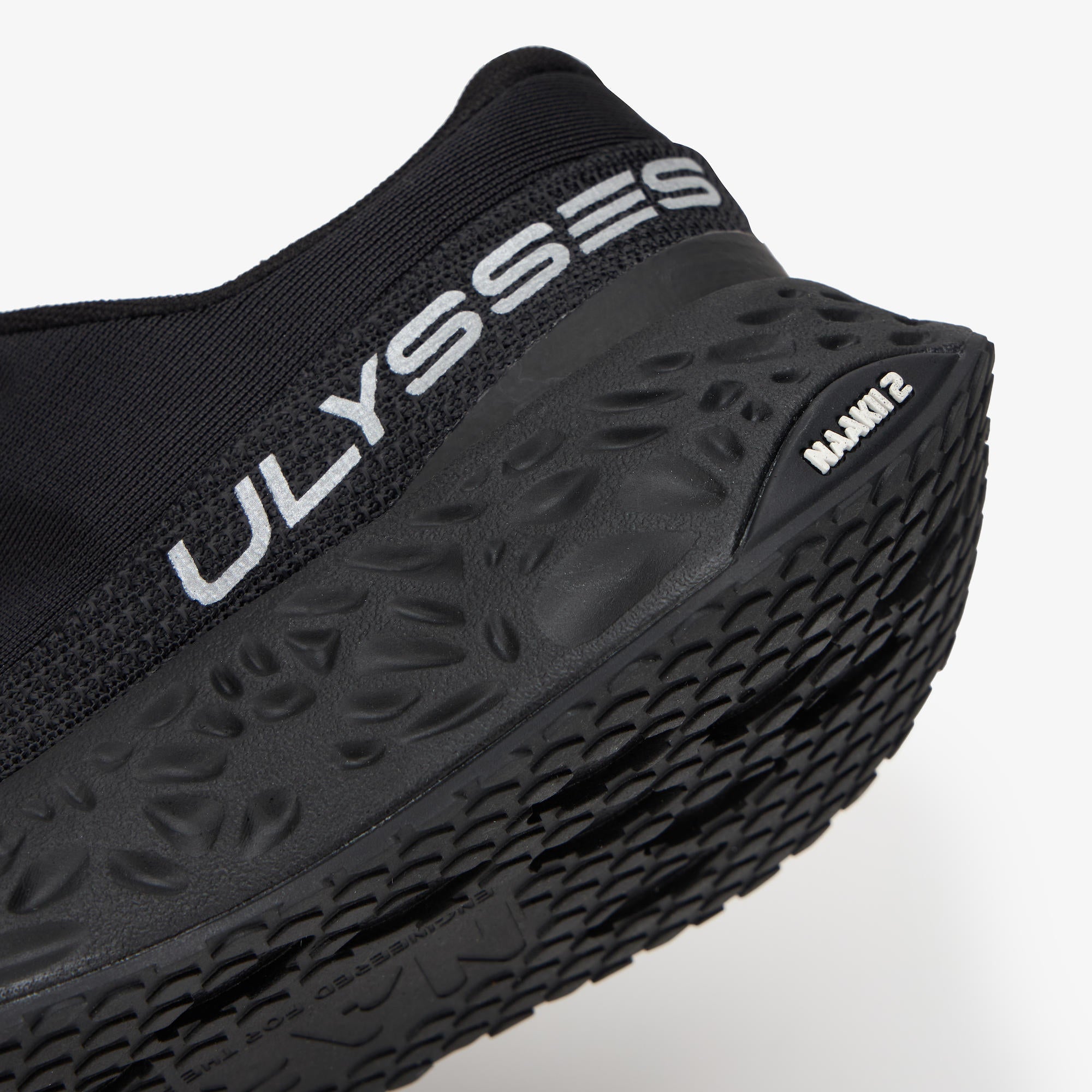 Close-up of a black Ulysses running shoe showing the textured sole, the brand name 'ULYSSES' in white on the heel collar, and 'NAAKII II' on the side of the outsole, set against a clean white background.