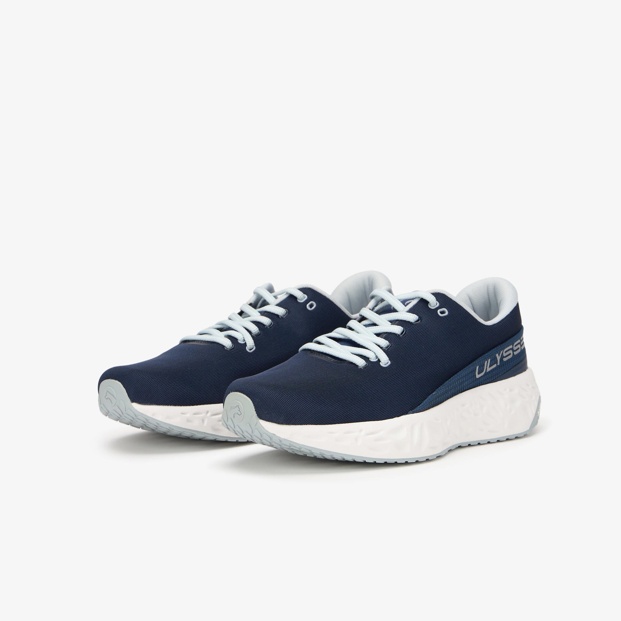 A pair of navy blue ULYSSES NAAKII  sneakers with white laces and a chunky white sole, shown on a light gray background. 