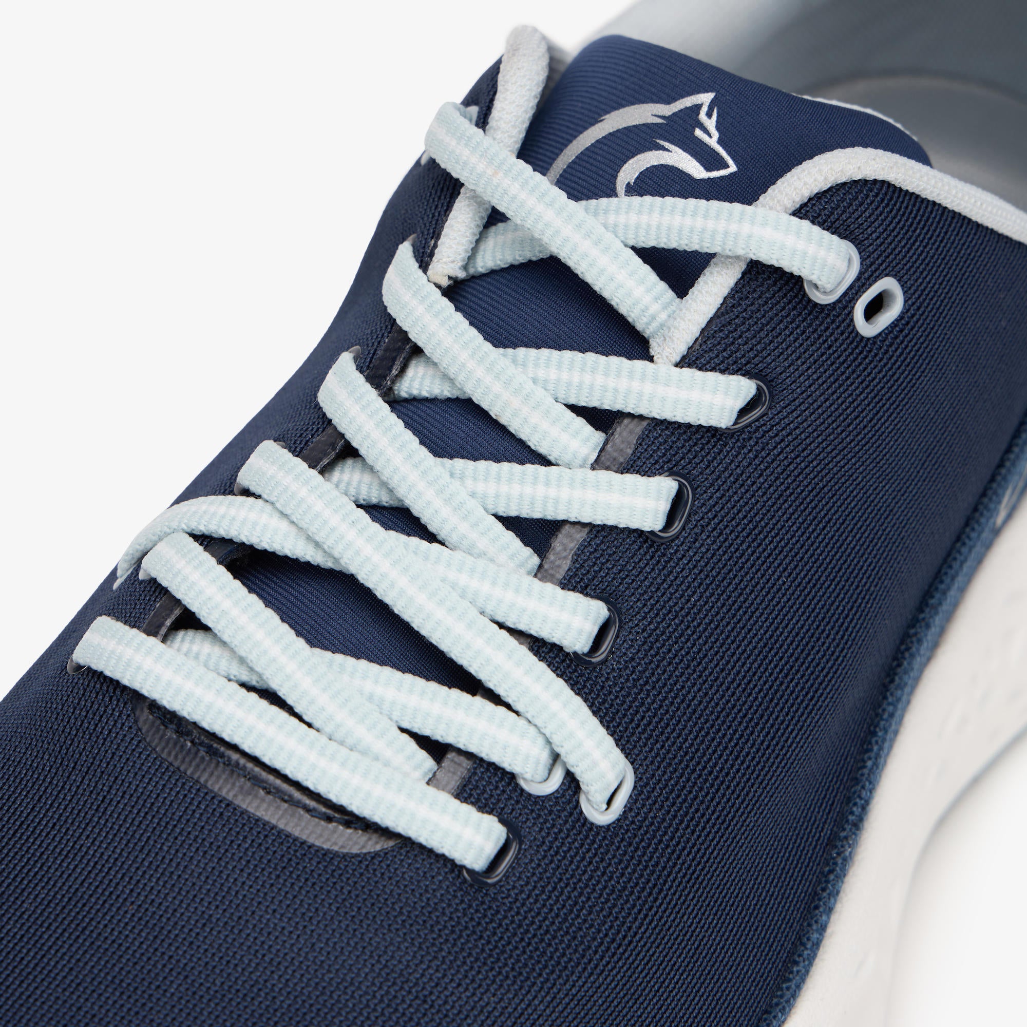 Close-up of a navy blue athletic shoe with light blue laces and a white shark logo on the side, set against a clean white background.