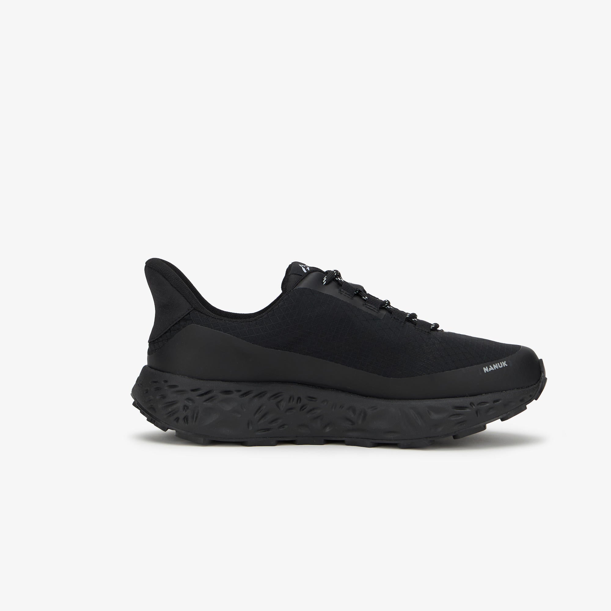 A black ULYSSES NANUK sneaker shown from the side against a light gray background. The shoe features a textured black sole