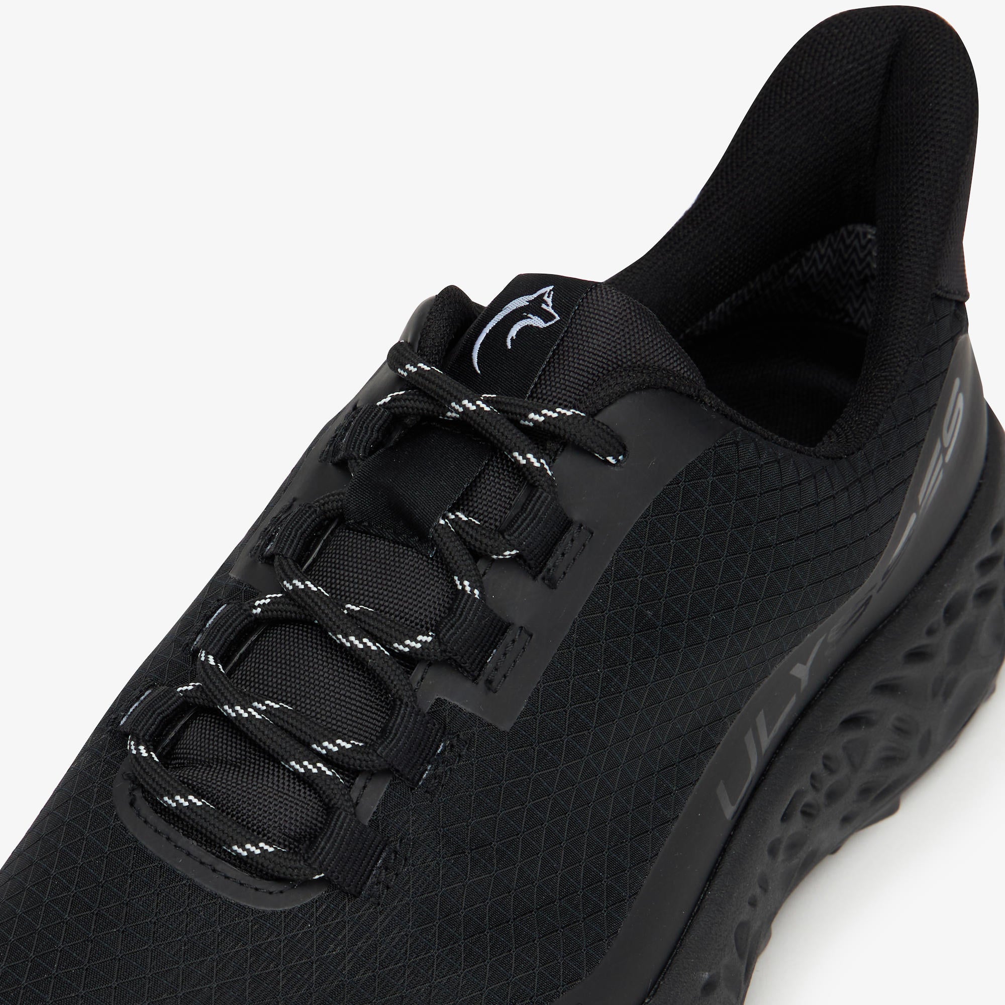 A close-up shot of a black ULYSSES NANUK sneaker with textured mesh panels, black laces with white stitching, and a black sole, shown against a plain white background.