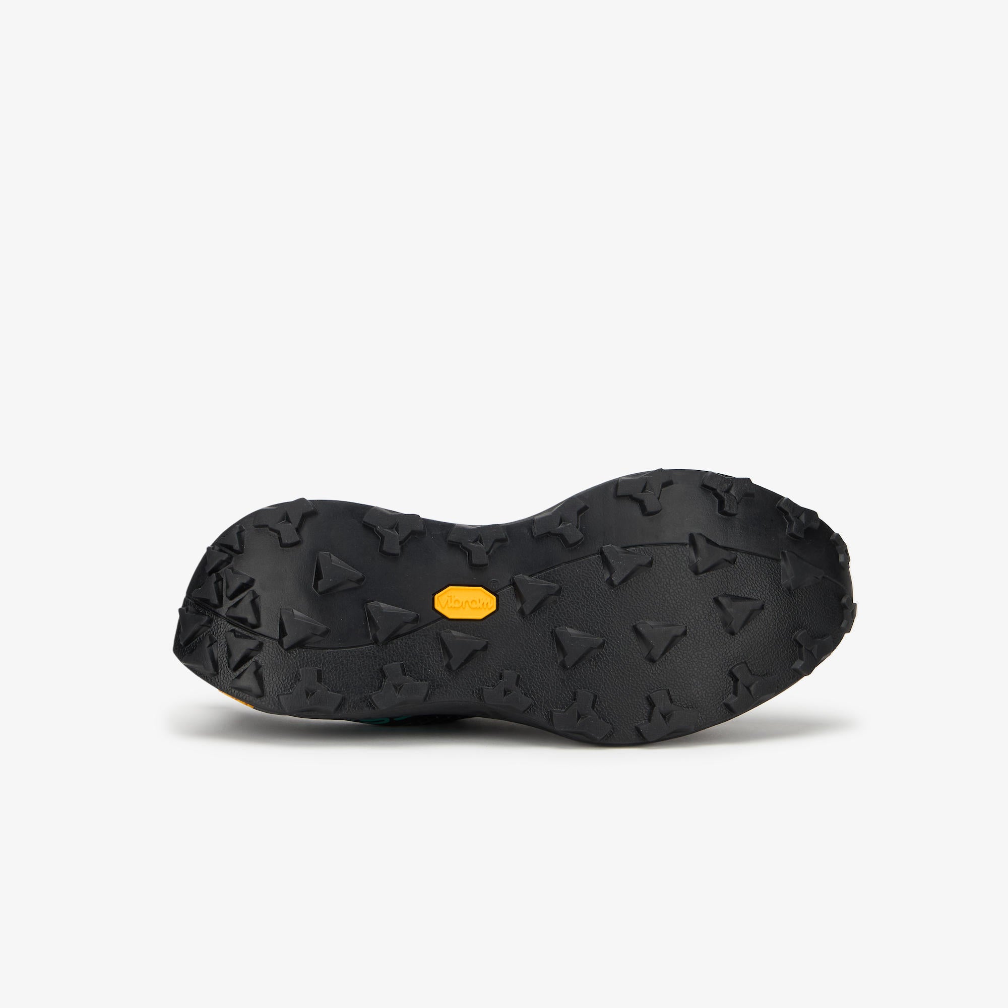 The black rubber outsole of a ULYSSES NANUK, featuring a textured tread pattern with small triangular and star-like grips and a small yellow Vibram logo in the center, shown against a light gray background.