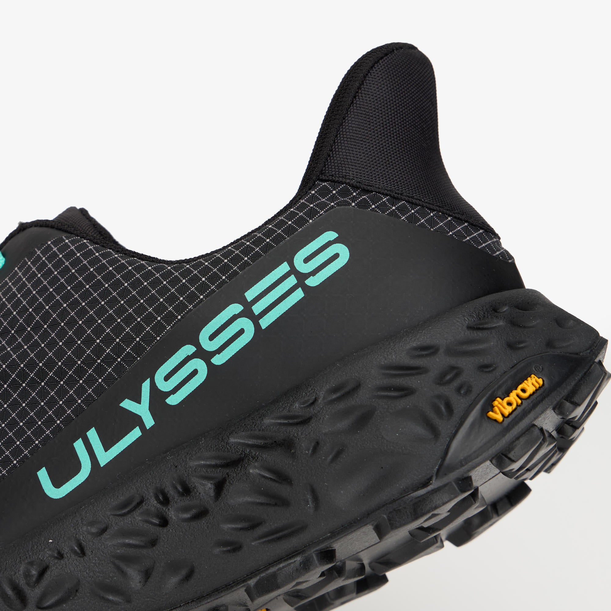 Close-up of a black trail running shoe showing the side profile with a black textured midsole, Vibram logo, and a mint green 'ULYSSES' brand name on the side.