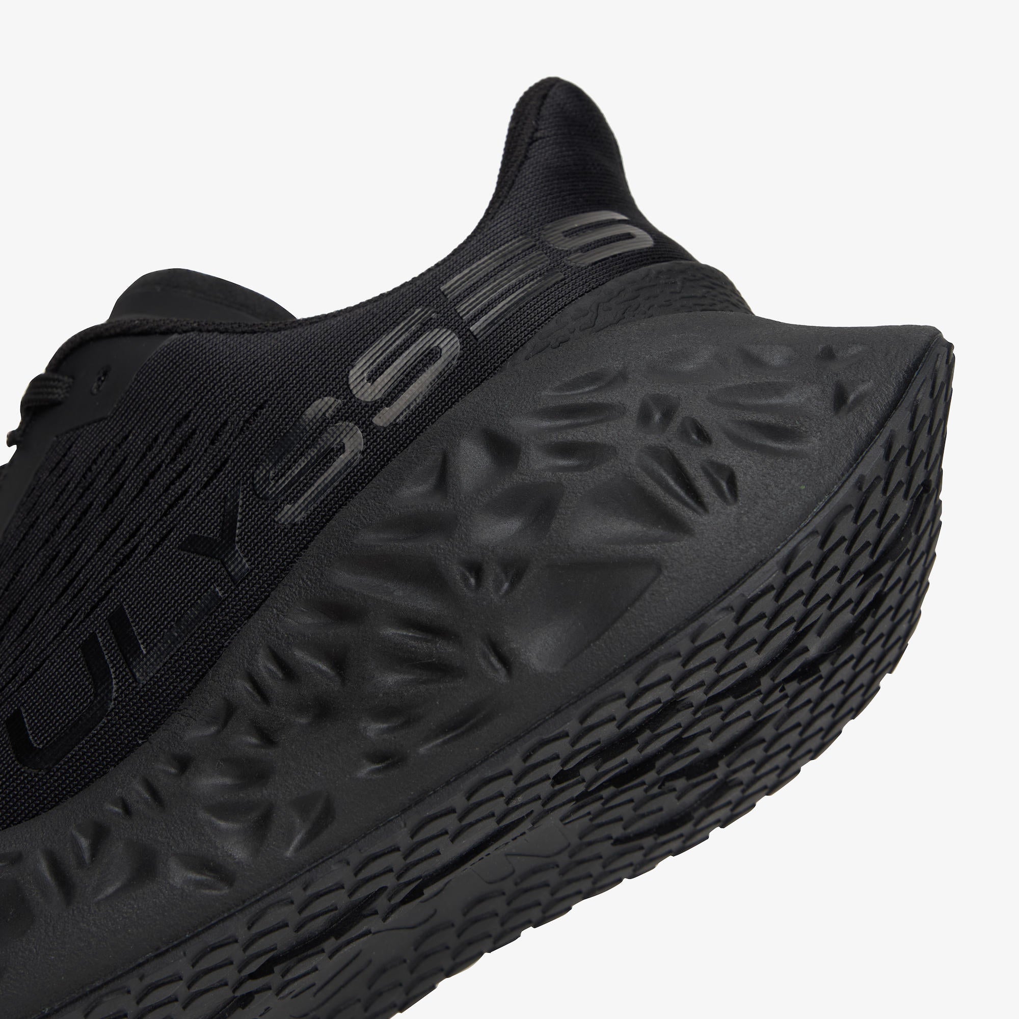 Close-up of a black running shoe showing the textured midsole and part of the upper with embossed branding on a light gray background.