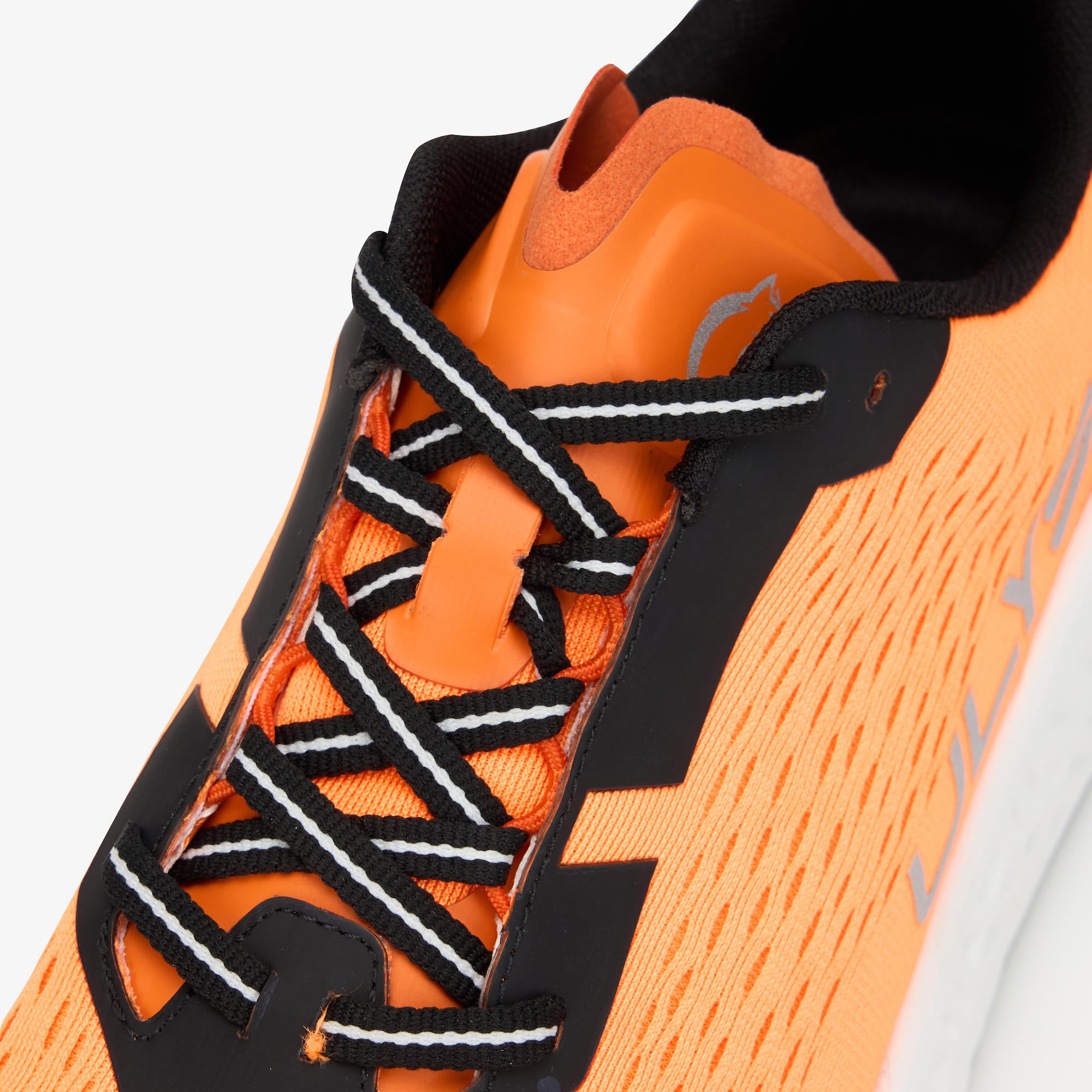 Close-up of a running shoe in bright orange and black, showing the side panel, black laces with white stripes, and part of the white outsole.
