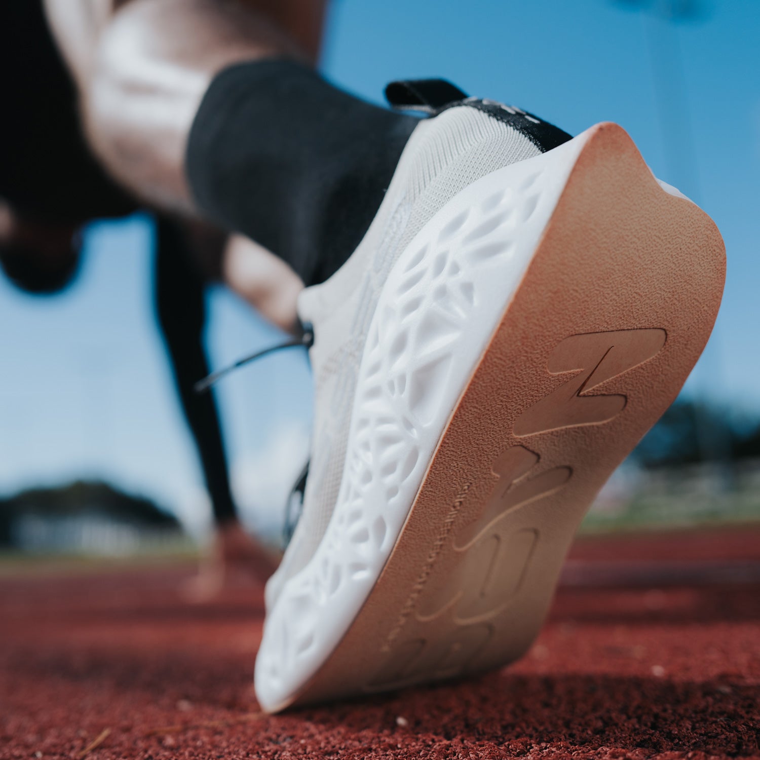 "Natural Adaptive Running System” – scarpa da corsa Ulysses chiara in fase di partenza su pista rossa, che mette in risalto la suola ammortizzata e il sistema adattivo per le performance su strada