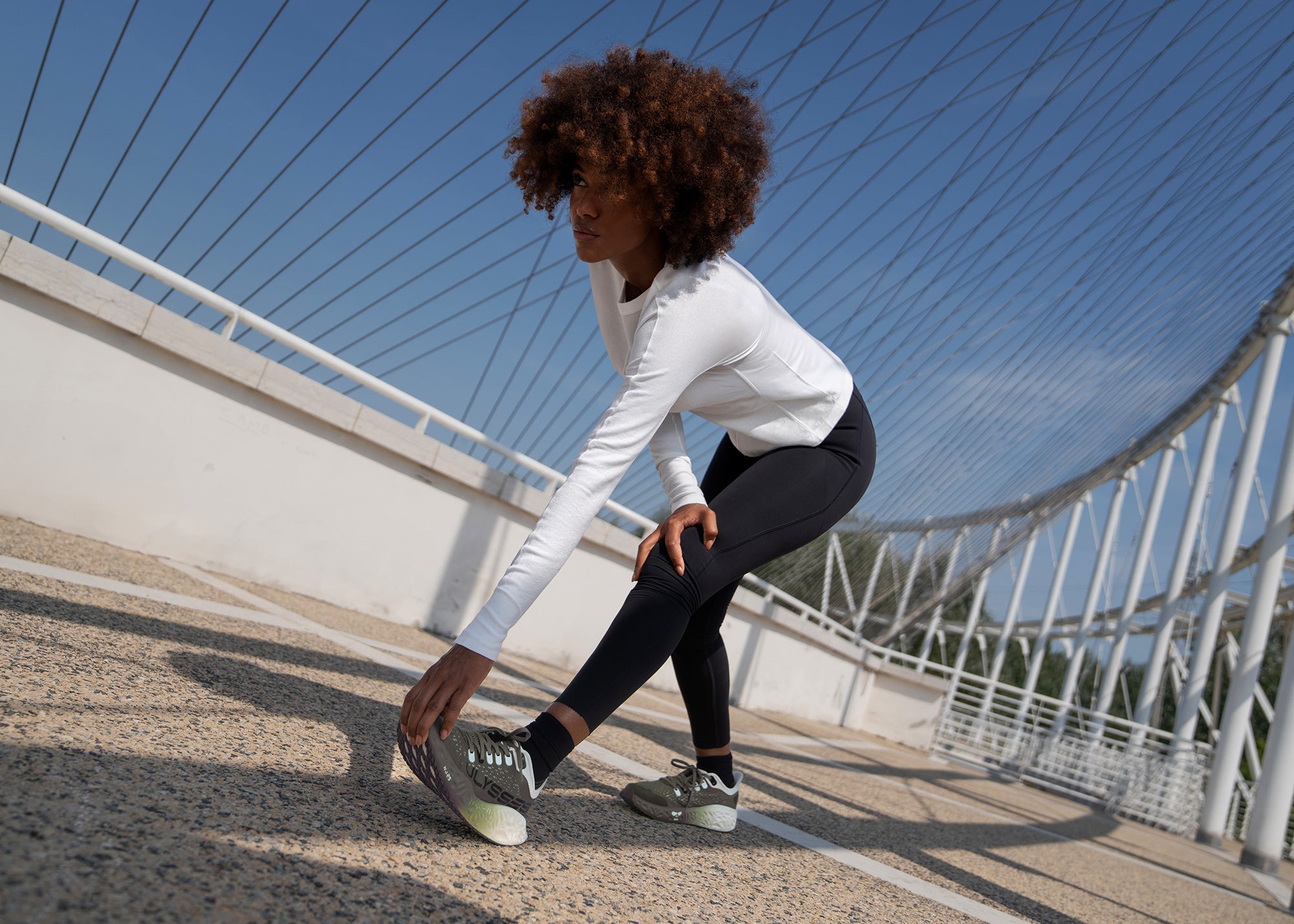 Road running shoes worn during outdoor stretch on bridge