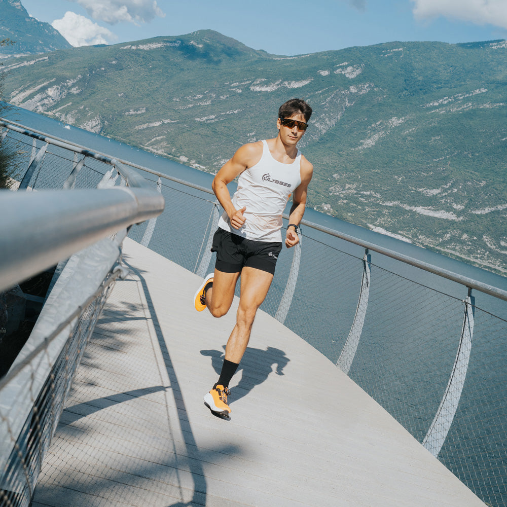 A man running on a modern elevated walkway with a scenic mountain and lake background